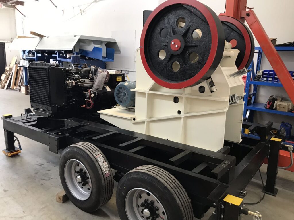 a machine with a red and black wheel sits on a trailer