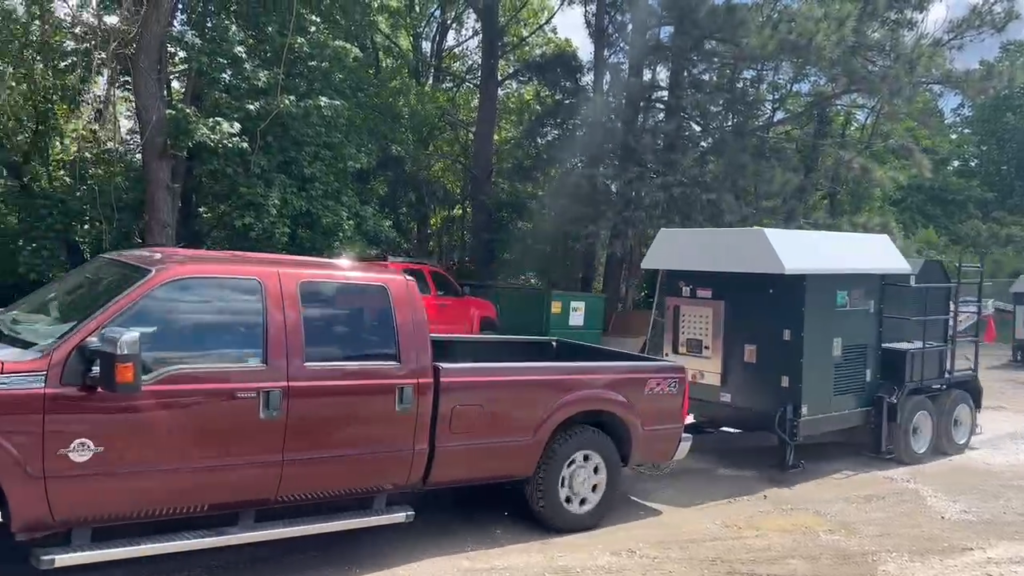 a red ford truck is parked next to towable rock crusher